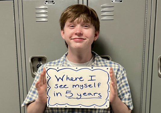 Devin Pierre (9)  holds a whiteboard that says ‘where I see myself in 5 years.   
